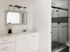 Bright bathroom featuring a white vanity, gray framed mirror, and glass shower with hexagon tile accent wall at 3147 W Phelps Rd, Phoenix, AZ 85053