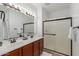 Bright bathroom featuring double sinks with wood cabinets, large vanity mirror, and glass-enclosed shower at 3467 S Falcon Dr, Gilbert, AZ 85297