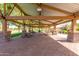 Large covered patio with stone pillars, picnic tables, and brick flooring overlooking grassy lawn at 3467 S Falcon Dr, Gilbert, AZ 85297