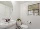 Well-lit powder room with pedestal sink, round mirror, and window with blinds for added privacy at 3467 S Falcon Dr, Gilbert, AZ 85297