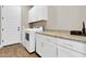 Well-organized laundry room with front-load machines, upper cabinets, and countertop space at 4342 E Ronald St, Gilbert, AZ 85295
