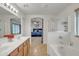 Bright bathroom with dual sinks, large mirror, bathtub and shower with a glass door at 45539 W Long Way, Maricopa, AZ 85139