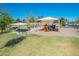 A vibrant community playground with shaded seating and picnic areas, perfect for Gathering fun and outdoor activities at 45539 W Long Way, Maricopa, AZ 85139