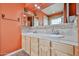 Bathroom featuring dual sinks with light-colored cabinets, an array of lights and tile backsplash at 4705 E Winston Dr, Phoenix, AZ 85044