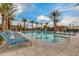 Beautiful community pool lined with palm trees and lounge chairs under a partly cloudy bright blue sky at 4832 S Ferric --, Mesa, AZ 85212