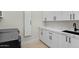 Bright laundry room featuring white cabinets, sleek hardware, and a modern black sink with light wood flooring at 6602 N Arizona Biltmore Cir, Phoenix, AZ 85016