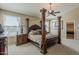 A luxurious main bedroom featuring a dark wood four-poster bed, side tables, and ample natural light at 9535 E Los Lagos Vista Ave, Mesa, AZ 85209