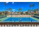 Well-maintained tennis court surrounded by palm trees and community residences under a clear blue sky at 9705 E Mountain View Rd # 1064, Scottsdale, AZ 85258