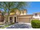 Two-story home features a stucco facade, two-car garage and covered porch with an arched entryway at 12030 W Polk St, Avondale, AZ 85323