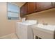 Functional laundry room with white washer and dryer, utility sink, and ample cabinet storage space at 12030 W Polk St, Avondale, AZ 85323