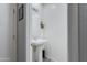 Compact powder room featuring a pedestal sink, mirror, and decorative accents at 14188 W Artemisa Ave, Surprise, AZ 85387