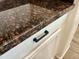Close-up of dark countertop with brown accents and white cabinetry with black hardware at 15093 W Glenrosa Ave, Goodyear, AZ 85395