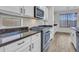 Bright kitchen featuring stainless steel appliances, dark countertops, white cabinets, and wood-look floors at 15093 W Glenrosa Ave, Goodyear, AZ 85395