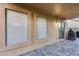 A covered back patio with tile flooring features screened-in windows and a door to the backyard at 15155 W Desert Hills Dr, Surprise, AZ 85379
