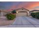 Charming single-story home featuring a well-maintained front yard and a two-car garage against a sunset sky at 15155 W Desert Hills Dr, Surprise, AZ 85379