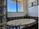 Bathtub featuring tile surround, glass block window, and an exterior view at 16401 S 29Th Dr, Phoenix, AZ 85045