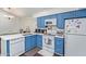 Modern kitchen with white appliances, blue cabinetry, and ample counter space at 1705 E Juanita Ave, Mesa, AZ 85204