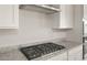 Close-up of a sleek gas stovetop with stainless steel hood and granite countertops in a modern kitchen at 17614 W Palo Verde Dr, Litchfield Park, AZ 85340
