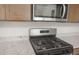 Close up of stainless steel gas range and microwave hood above granite countertops at 17633 W Palo Verde Dr, Litchfield Park, AZ 85340
