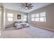Spacious main bedroom featuring plush carpet, a ceiling fan, and lots of natural light from the many windows at 17962 W Elm St, Goodyear, AZ 85395