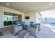 Covered outdoor patio with comfortable lounge seating, TV, and poolside view at 17962 W Elm St, Goodyear, AZ 85395