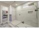 Tiled shower with rainfall shower head and bench in the en suite bathroom with access to a closet at 17962 W Elm St, Goodyear, AZ 85395