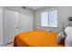 Comfortable bedroom featuring an orange quilt, closet with bi-fold doors and a window with adjustable blinds at 17988 W Deneen Way, Surprise, AZ 85374