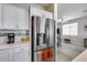Kitchen with stainless steel refrigerator and white cabinets, next to a living area with wood flooring at 17988 W Deneen Way, Surprise, AZ 85374