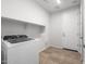 Well-lit laundry room with modern appliances, tile floors, and storage shelves at 21292 N 270Th Dr, Buckeye, AZ 85396