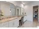 Bright bathroom with granite countertop vanity, dual sinks, and an open doorway to the walk-in closet at 24270 N 173Rd Ave, Surprise, AZ 85387