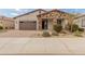 Charming single-story home featuring a stone facade, desert landscaping, and a brick-paved driveway at 24270 N 173Rd Ave, Surprise, AZ 85387