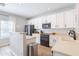 Bright kitchen featuring white cabinets, black appliances, and a serving counter at 2469 S Sailors Ct, Gilbert, AZ 85295