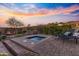 Outdoor space featuring a jacuzzi, patio, fire pit, lounge chairs, and desert landscaping at dusk at 2550 W Pumpkin Ridge Dr, Anthem, AZ 85086