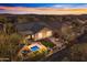 Aerial view of a backyard with a sparkling pool, fire pit, and beautifully landscaped seating area at sunset at 2550 W Pumpkin Ridge Dr, Anthem, AZ 85086
