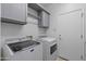 Bright laundry room featuring a modern washer and dryer, gray cabinets, and a convenient hanging rod at 2550 W Pumpkin Ridge Dr, Anthem, AZ 85086