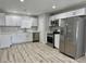 Modern kitchen featuring stainless steel appliances, white cabinets, and stylish wood-look flooring at 2634 N 52Nd Ave, Phoenix, AZ 85035