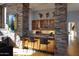 A stylish bar area with custom cabinetry, stone pillars, modern lighting, and unique artistic wall decor at 29218 N 107Th Way, Scottsdale, AZ 85262