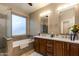 Bright bathroom featuring double vanities, a soaking tub, and a separate glass shower at 29374 N 68Th Ln, Peoria, AZ 85383
