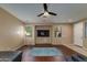 Well-lit living room with a mounted TV, ceiling fan, and dark wood floors at 29374 N 68Th Ln, Peoria, AZ 85383