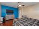 Main bedroom featuring wood floors, a ceiling fan, and a bright blue accent wall behind the bed at 29374 N 68Th Ln, Peoria, AZ 85383