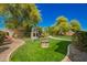 Backyard features a playset, stone firepit, manicured lawn, and mature trees at 3046 E Athena Ave, Gilbert, AZ 85297