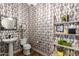 Stylish powder room featuring decorative wallpaper, a pedestal sink, and shelving at 3046 E Athena Ave, Gilbert, AZ 85297