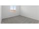 An empty bedroom with gray carpet, white walls, and a window, ready for customization and personalization at 37650 W Nina St, Maricopa, AZ 85138