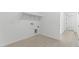 Clean laundry room with overhead shelves and wood-look tile floors at 37650 W Nina St, Maricopa, AZ 85138