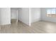 Spacious living room with light wood-look floors and abundant natural light from a large window and door at 37650 W Nina St, Maricopa, AZ 85138