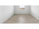 An empty room with light wood-look floors, white walls, and a window, ready for customization and personalization at 37650 W Nina St, Maricopa, AZ 85138
