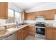 A well-lit kitchen featuring granite countertops, wood cabinets and stainless steel appliances at 3805 S 73Rd Dr, Phoenix, AZ 85043