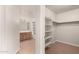 Spacious walk-in closet with built-in shelves and ample storage space, leading to a bathroom at 3805 S 73Rd Dr, Phoenix, AZ 85043