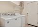 Bright laundry room with washer, dryer, and shelving for organized storage at 41444 W Capistrano Dr, Maricopa, AZ 85138