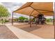 Community playground with a large shade structure, offering a fun and safe play area for children at 41444 W Capistrano Dr, Maricopa, AZ 85138